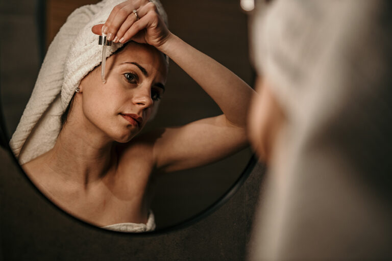A Woman Is Using Anti Aging Serum Treatment On Her Face In The Bathroom