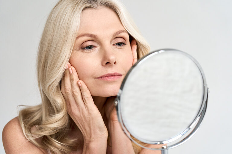 Closeup Portrait Of Gorgeous Happy Middle Aged Woman Looking At Mirror Touching Her Skin