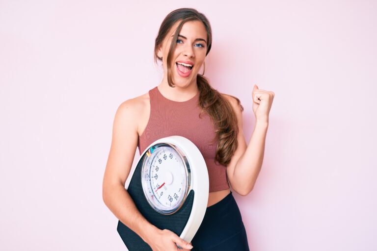 Beautiful Young Caucasian Woman Holding Weight Machine To Balance Weight Loss Screaming Proud, Celebrating Victory And Success Very Excited With Raised Arms
